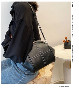 Detail of black PU shell bag with white cross-stitching and metal chain strap