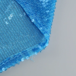 Detailed macro view of shimmering blue sequins and mesh fabric on the split dress hem
