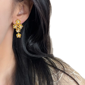 Vintage gold flower drop earrings with zircon crystals shown on a female model