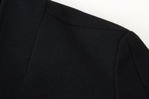 Gros plan sur la couture de l'épaule et la texture de laine d'un manteau noir élégant