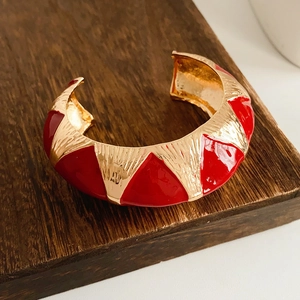 Detail of vintage gold C-shape cuff bracelet with red enamel and engraved patterns