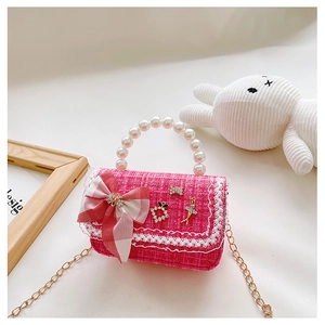Detailed view of pink tweed kids bag with pearl handle and lace trim on white fur