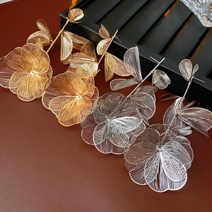 Macro detail of large hollow metal flower earrings with textured brushed gold and silver finish
