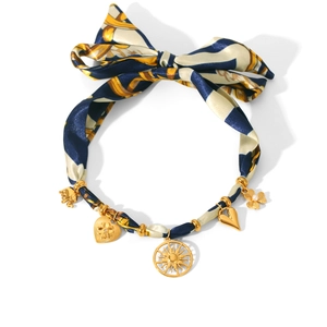 Detail of silk ribbon necklace with golden sun, elephant, and heart-shaped charms