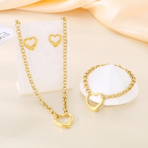 Detailed view of golden heart jewelry set with necklace bracelet and stud earrings on silk