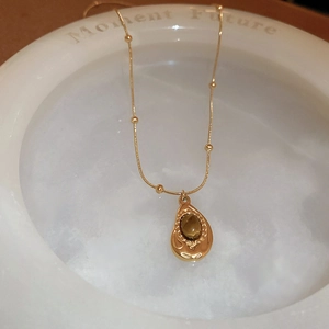 Detailed shot of retro gold necklace with a brown tiger eye stone pendant on a white tray