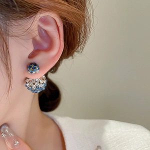 Detail of vintage double-sided blue rhinestone stud earrings worn on a female ear