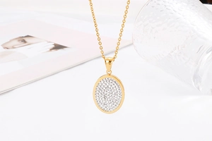 Detail of a gold oval pendant necklace with shimmering white zircon inlay for women