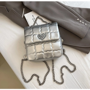 Detailed flat lay of a silver quilted mini bag with heart logo and chain straps