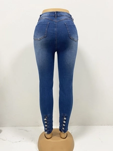Détail d'un jean skinny taille haute avec cinq boutons métalliques verticaux à l'ourlet