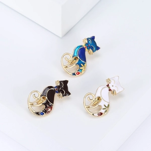 Detailed close-up of blue, black, and white enamel cat brooches with gold accents