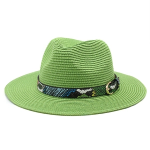 Detail of green straw fedora hat featuring a stylish snakeskin band and golden buckle