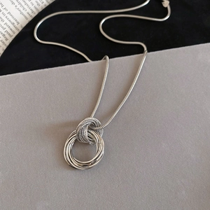 Detailed view of layered silver circular pendant with textured rings and snake chain