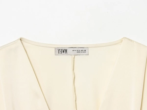 Détail du col en V sur chemise en satin beige clair avec étiquette de taille et marque
