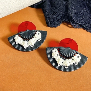 Detail of fan-shaped earrings with 3D white roses and red circular accents on black base