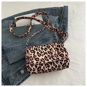 Detailed top view of leopard print crossbody bag on denim jacket backdrop