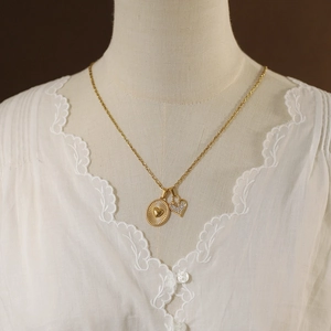 Detail of a gold-plated vintage sun and heart pendant necklace worn by a model