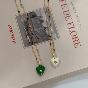 Detail of colorful enamel heart pendants with gold chains on a chic fashion magazine