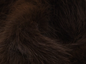 Macro shot of fluffy dark brown faux fur texture with silky finish and soft touch details