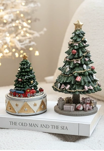 Close-up of decorative Christmas tree figurines with train base and pink bow details