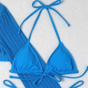 Detailed flat lay of a royal blue halter bikini top on a soft white plush background