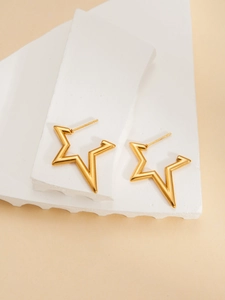 Minimalist gold star earrings displayed on geometric stones in a soft-toned setting