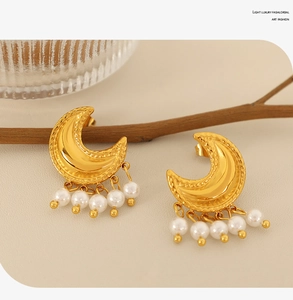 Detail von goldenen Mond-Ohrringen mit weißen Perlen auf elegantem beigem Hintergrund