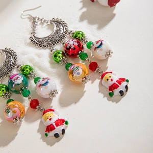 Macro detail of beaded Christmas Santa earrings with crescent metal and snowflake patterns