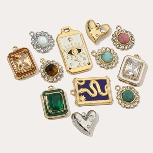 Assorted gold stainless steel charms with evil eye, snake, and heart gemstone designs