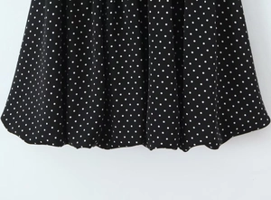 Détail macro de la robe vintage noire à pois avec une texture plissée légère et élégante