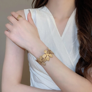 Dettaglio del set bracciale e anello a fiore dorato con texture metallica su modella