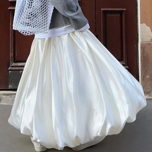 Close-up of white satin midi skirt with elegant voluminous hem and silky texture finish