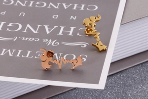 Macro shot of gold and rose gold elephant heartbeat earrings on a book page