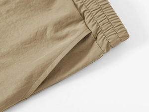 Detail of khaki cargo shorts showing elastic waistband and reinforced side pocket stitching