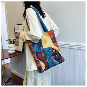 Lifestyle shot of a cat illustration tote bag worn over the shoulder by a model