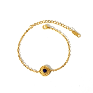 Détail du bracelet en acier doré avec pendentif soleil serti d'une pierre turquoise