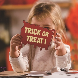 Child holding Halloween Trick or Treat sign prop with pumpkin and ghost motifs