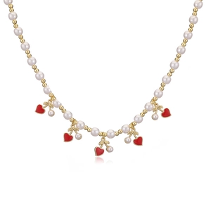 Detail of pearl bead necklace with red heart pendants and golden beads on white surface