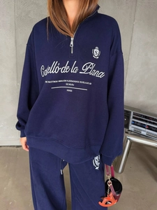 Detail of navy blue half-zip sweatshirt with vintage lettering and embroidered badge