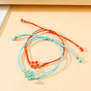 Detail of hand-woven cord bracelets featuring colorful enamel flowers and small pearl charms