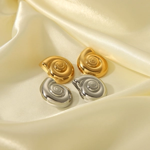 Dettaglio macro di orecchini a spirale in oro e argento su tessuto di seta pregiata