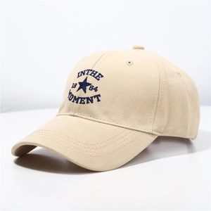Detailed close-up of blue IN THE MOMENT embroidery on beige cotton twill baseball cap