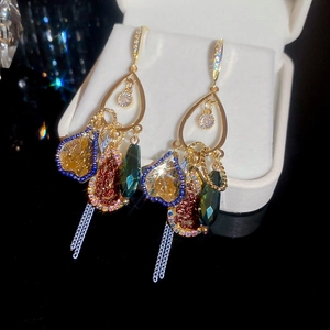 Macro shot of vintage teardrop earrings with colorful gems and metallic tassel fringe