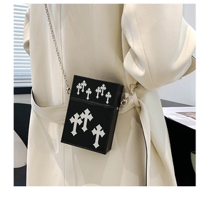 Detail of black gothic crossbody bag with white cross patches and silver metal chain