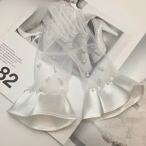 Detail of white bridal lace gloves with pearls and pleated satin cuffs on a magazine