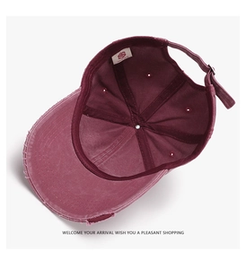 Detail of distressed burgundy baseball cap featuring interior stitching and adjustable strap