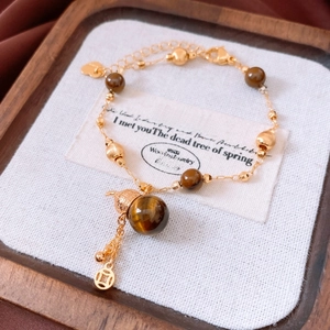 Detailed shot of tiger eye beads with a gold coin pendant and vintage chain bracelet