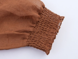 Macro shot of smocked elastic cuffs and ruffle detail on caramel linen dress sleeves