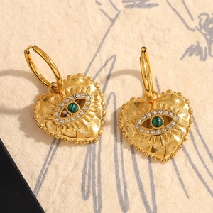 Macro detail of 18K gold plated heart earrings with malachite stone and zircon eye