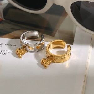 Close-up of gold and silver heart rings with charms on a fashion magazine background